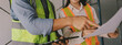 © ARMMY PICCA - Construction manager and engineer dressed in orange work vests and hard helmets explore construction documentation on the building site near the steel frames