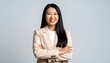 © Nangkir - Confident businesswoman in a light beige blazer smiles warmly against a neutral backdrop.