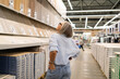 © Ivan Traimak - Woman shopping for home materials in a spacious hardware store during the day while assessing options on display shelves