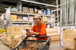 © Ivan Traimak - Senior woman shopping for home improvement supplies while using her smartphone inside a warehouse store