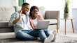 © Prostock-studio - Cheerful african american couple waving at laptop screen, having video call with friends or relatives, home interior. Young black lovers making online party with family, smiling, copy space