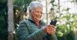 © peopleimages.com - Nature, happy and senior woman with phone for texting, communication or mobile app for weekend trip. Smile, forest and elderly female person with cellphone for chatting online outdoor on holiday.