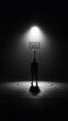 © herlambang - Shadowy figure gazes at a lit basketball hoop, under an intense spotlight, on a dark court