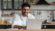 © Johannes - smiling indian business man working on laptop at home office young indian student or remote teacher using computer remote studying virtual training watching online education webinar at home office no