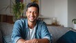 © Johannes - portrait of happy mid adult man sitting on sofa at home handsome latin man in casual relaxing on couch and smiling cheerful indian guy looking at camera  no logos no brands ar 169