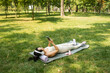 © Mykola - Cute Asian woman wearing sports sitting on city park, outdoor holding mobile phone while relaxing after exercising. Sport, technology and healthy lifestyle concept.