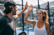 © EricMiguel - Happy young man and woman high-fiving after a game of paddle tennis on an outdoor court