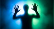 © Hilmi - Dark silhouette of a person with hands pressed against a frosted surface illuminated by blue and green light.