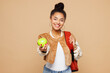 © ViDi Studio - Young smiling smart girl student wear casual clothes backpack bag hold eat green apple stretch hand to camera isolated on plain pastel light beige background. High school university college concept.