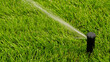 © Yuliya - Lush green lawn being watered by automated sprinkler head, with fine spray of water arcing across grass. Automatic equipment for irrigation and maintenance of lawns, gardening, landscaping.