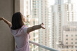 © fizkes - Embracing experiences. Carefree young female tourist stand by panoramic window in hotel suite with arms wide open enjoy modern cityscape panorama feel freedom joy of discovering new city. Copy space