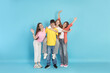© New Africa - Full-length portrait of happy teenage friends on light blue background