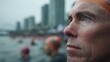© Justlight - Focused medium shot on a participants concentrated face wearing a swim cap with the hazy outline of an urban waterfront and fellow swimmers in the background.