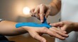 © Jiaa - Physical Therapist Applying Blue Kinesiology Tape on Arm in Clinic