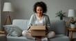 © PrabuanaAndika - Smiling Young Woman Excitedly Unboxing a Package at Home, Surrounded by Cozy Living Room Decor, Concept of Online Shopping and Surprise