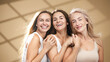 © wedmoments.stock - Three joyful women with radiant skin, embracing each other in a wellness spa setting, showcasing natural beauty and friendship, illuminated by soft light with a serene ambiance and warm tones