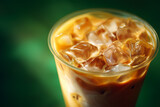 Close up of iced coffee with swirling cream and ice cubes in clear plastic cup coffee drink beverage