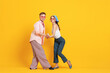 © New Africa - Happy couple in retro outfits dancing on orange background, space for text