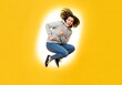 © MdRaselMahmud - Young woman in hoodie and jeans jumping with joy against a yellow background