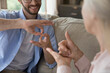 © fizkes - Intergenerational communication using sign language. Close up young man aged woman hold nonverbal conversation with hand gestures. Inclusive dialogue support for person with hearing disability concept