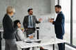 © Novak - Group of four business professionals discussing ideas in a modern office