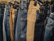 © Caroline - A close-up view of many shades and types of denim jeans hanging on a rack. Abstract fashion background or banner with copy space. Economy and industry design element.