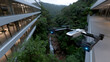 © Jovana - A drone soars above a tropical landscape, capturing the essence of nature, technology, and modern architecture with a waterfall cascading in the background.