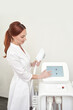 © elenavolf - Caucasian female technician operates laser hair removal machine in clinic setting.