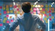 © Ammad - Mulling over ideas on a glass wall covered with colorful sticky notes in cool toned office lighting