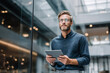 © Poj - Confident professional man holding tablet in modern office interior