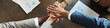 © pressmaster - Diverse group of young adult and middle aged men and women stacking hands in teamwork gesture on wooden table, showing multiethnic collaboration during business meeting from top view