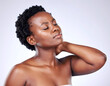 © fara - Relaxed African American woman with glowing skin touching her neck, eyes closed, depicting self-care and beauty.