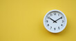 © Noor  - Modern white analog clock showing time on bright yellow wall, concept of punctuality