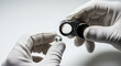 © Bakha - Expert jeweler with white gloves inspecting sparkling round diamond gemstone using magnifying loupe for clarity evaluation and quality assessment in professional laboratory setting