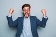 © TuruMuru - Attractive young man in a suit ecstatic and celebrating with raised arms smiling and shouting for victory