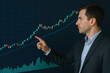 ©  JAMAL PRODUCTION - Professional businessman analyzing a rising stock market chart, pointing to a successful growth trend. Financial investment strategy.