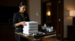 © delila - Smiling hotel housekeeper with fresh towels and luxury amenities for guest room service.