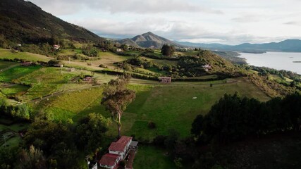 Wall Mural - Zoom in aerial footage of Guatavita countryside, showing green fields, rural houses and distant mountains on a sunny day.