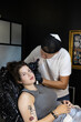 © YuliaSmyt - Smiling tattoo artist prepares for the session while a young woman relaxes in the chair, moments before getting a tattoo in a professional studio