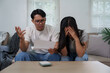 © Phimwilai - Stressed couple facing financial problems reading documents at home