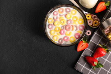 Wall Mural - Bowl of colorful sweet cereal rings with milk and strawberries on black table