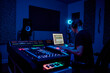 © AnnaStills - Young adult Caucasian man wearing headphones working at audio mixing console and computer in professional recording studio, focusing on music production and sound editing