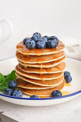 Wall Mural - Plate with delicious pancakes and blueberries on white table