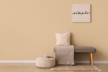 Poster - grey bench with cushion, blanket and pouf near beige wall