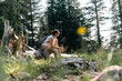 © olezzo - Traveling and walking in the forest. Woman resting sitting on a log in the forest, Nordic walking poles nearby