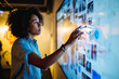 © AI_images_for_people - Young adult Black woman assembling a digital mood board for brand refresh ideas, dragging visuals on a touchscreen board