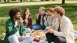 © Alice - A group of diverse young adult friends having a casual picnic conversation in the park. Concept of community, authentic connection, gen z lifestyle and digital detox.