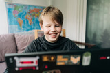A teenage boy uses a laptop for online communication while sitting in a room at home.