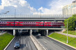 © Irina Mikhailichenko - Moscow, Russia - 05.31.2025: Aeroexpress train from Sheremetyevo airport on the bridge on Kuntsevskaya metro station of Moscow central diameters. Car traffic on Rublevskoe highway.