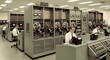 © Lauri - Vintage Computer Room with Men in White Shirts Operating Mainframes and Tape Drives